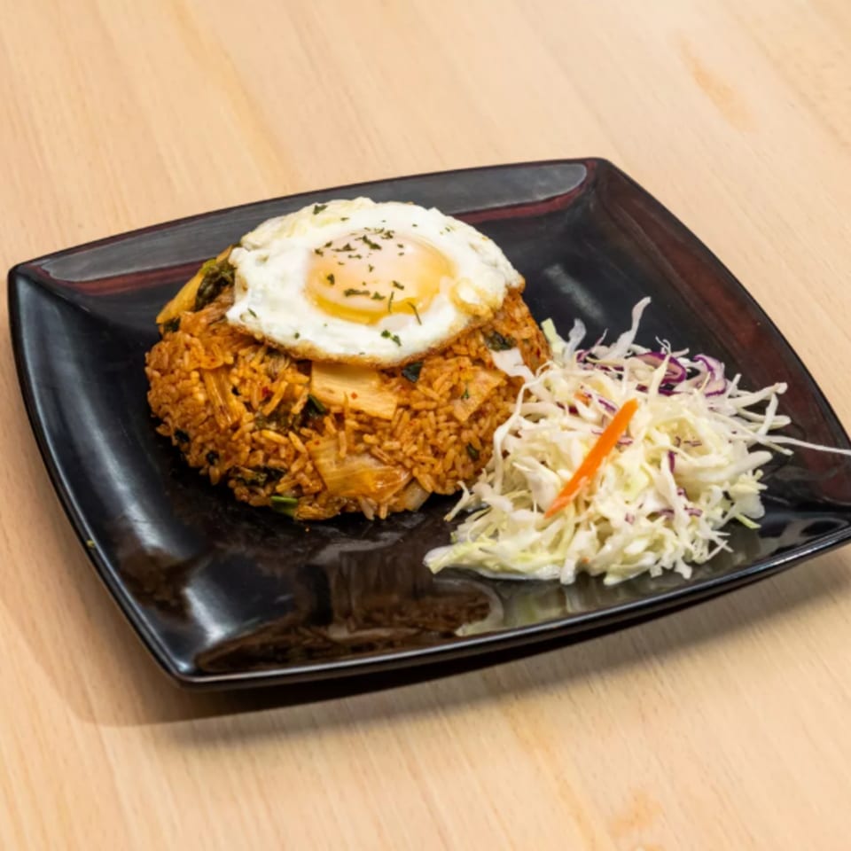 Kimchi fried rice with a fried egg on top and a side of shredded cabbage salad.